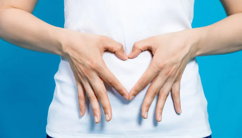 Learn more about Stomach Cancer Women makes a heart shape with her hands over her stomach