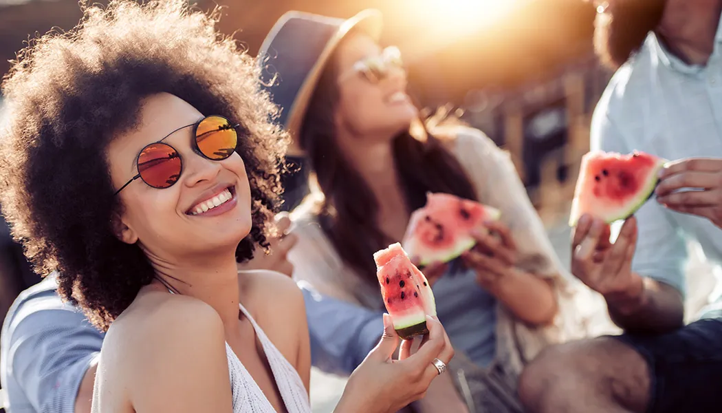 Cheerful,Young,Friends,Eating,Watermelon,On,Beach,having,Fun,Together. Cheerful young friends eating watermelon on beach,having fun together.