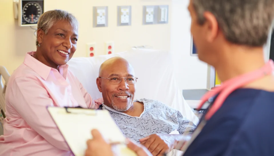 Husband and Wife look hopeful speaking to Doctor in hospital