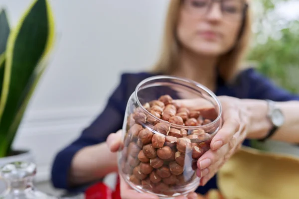 Woman holding a jar of hazelnuts - Nut-Consumption and Breast Cancer Prevention and Survival