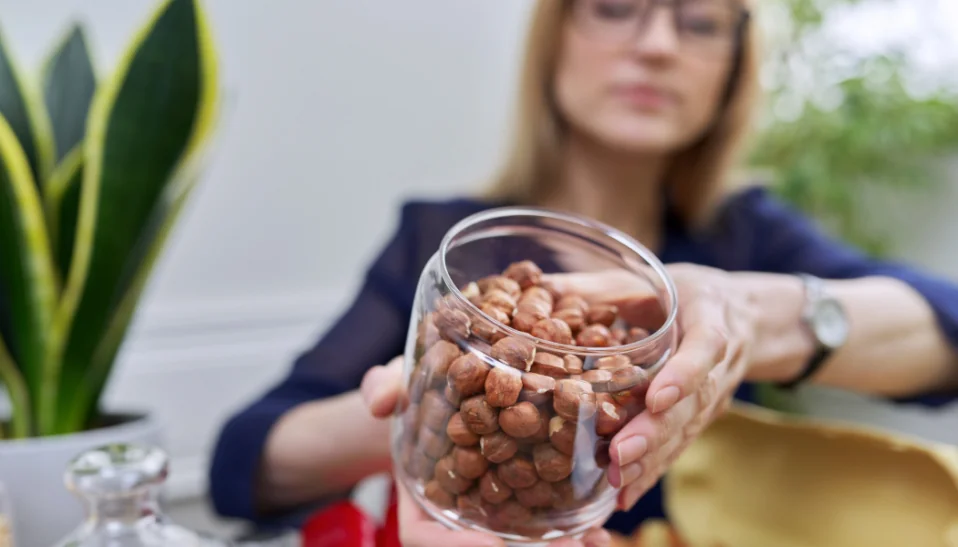 Woman holding a jar of hazelnuts - Nut-Consumption and Breast Cancer Prevention and Survival